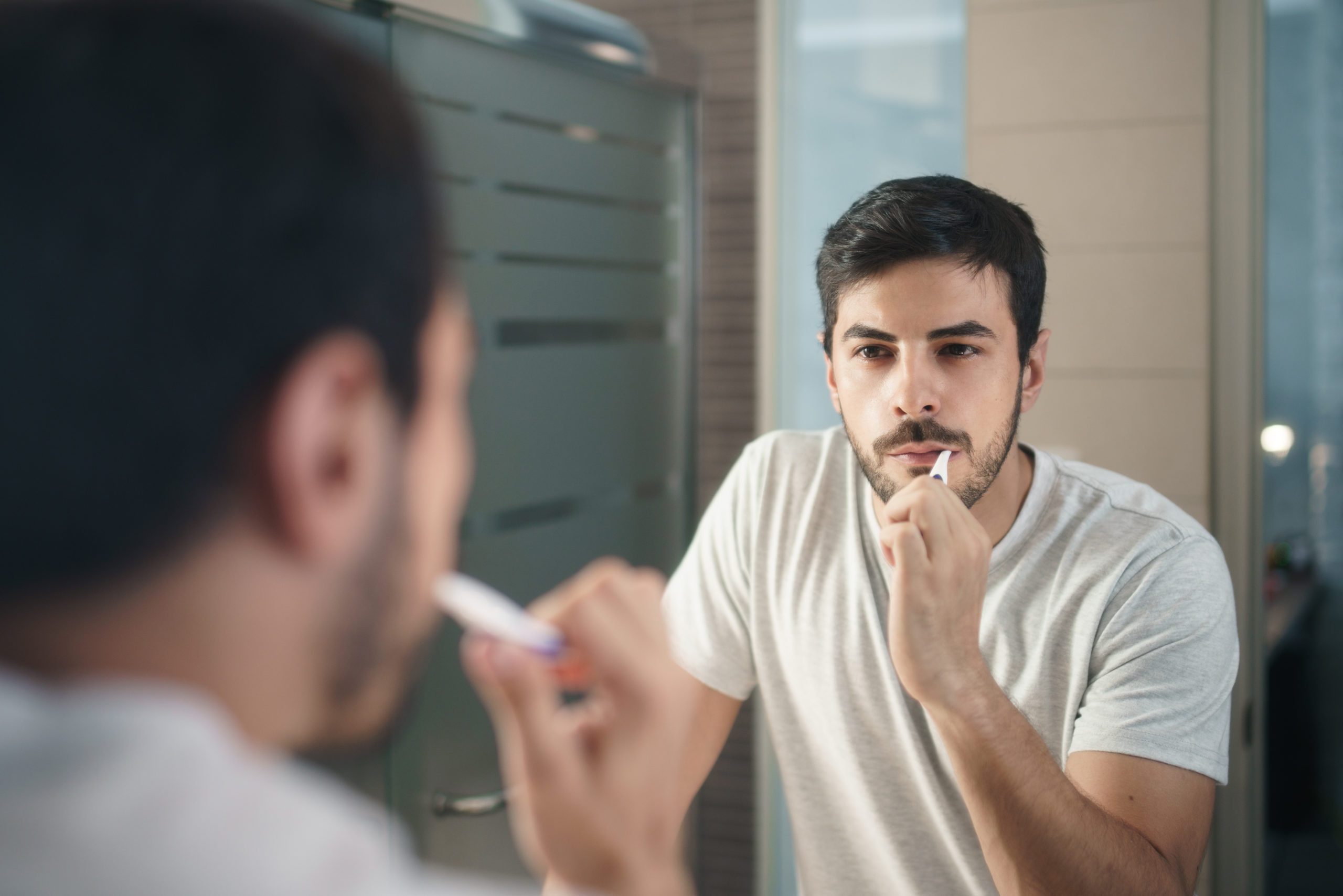 Man with beard grooming in bathroom at home for morning routine and body care.