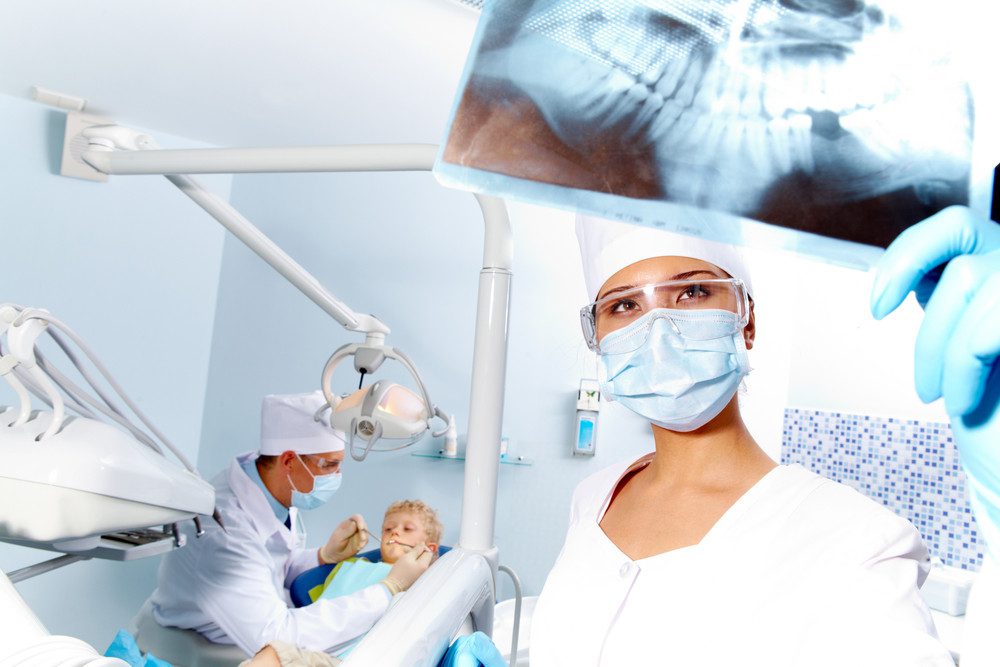 Portrait of assistant looking at patient x-ray photography during dental examination